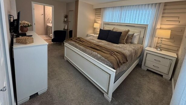 Un dormitorio con cama, mesitas de noche, escritorio y silla.