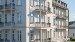 Un edificio de varios pisos con balcones, una escalera y un césped bien cuidado.