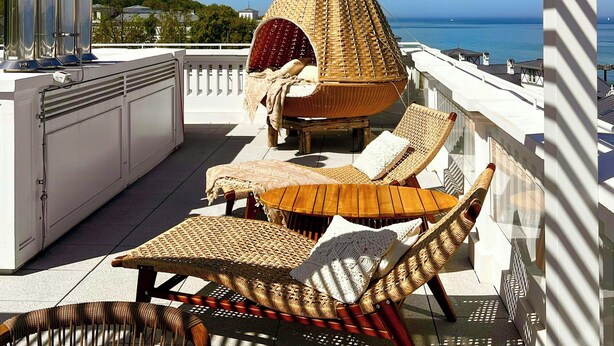 Una terraza en la azotea con una silla colgante, sillones de descanso y vistas al mar.