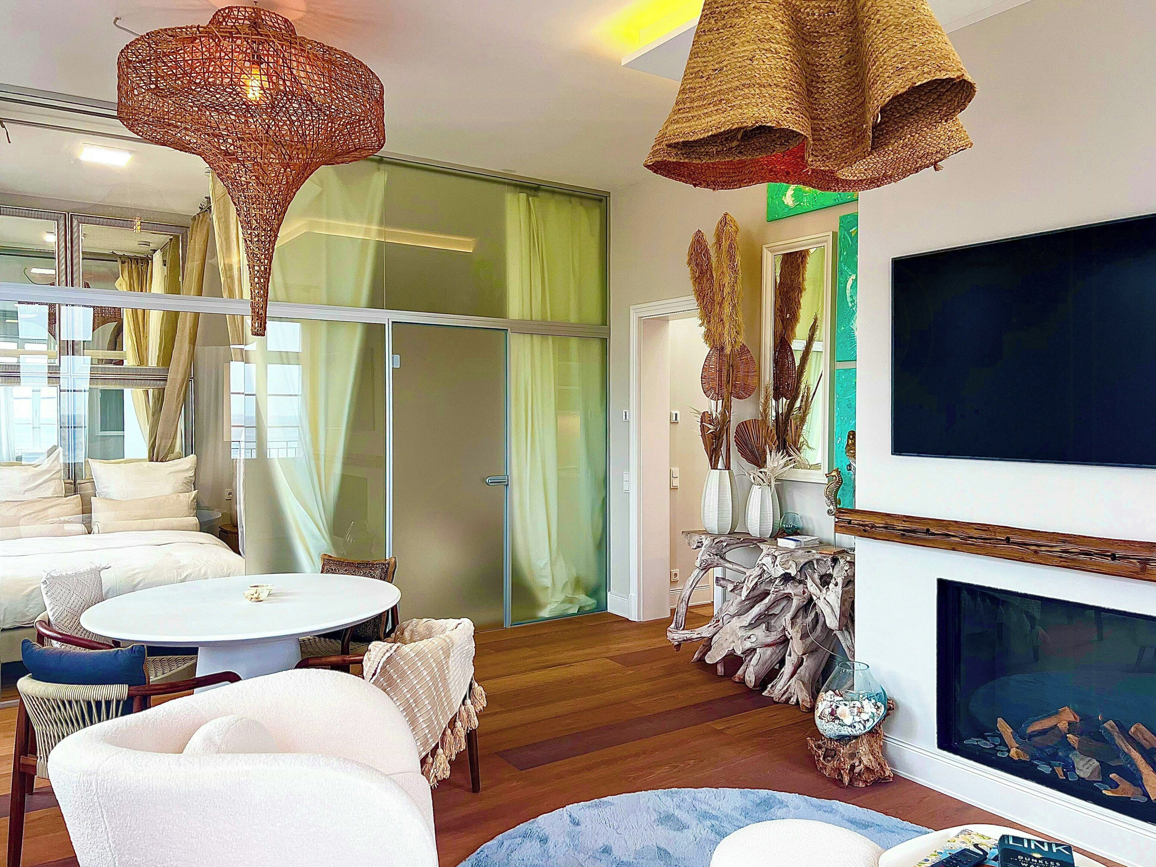 Una sala de estar moderna con chimenea, un televisor grande y un comedor con una mesa redonda y sillas.