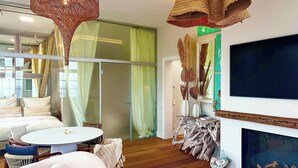 Una sala de estar moderna con chimenea, un televisor grande y un comedor con una mesa redonda y sillas.