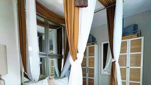 Un dormitorio con una cama con dosel, una mesita de noche, un espejo y un armario.