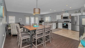 Una cocina moderna con zona de comedor, que incluye una mesa de madera, sillas y una lámpara colgante.