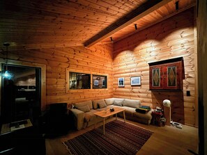 Indretning i en hyggelig træhytte med sofa, sofabord og tæppe.