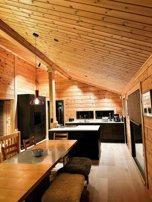 Eine moderne Küche mit Holzvertäfelung, einem Essbereich mit einer Bank und einer großen Kochinsel.