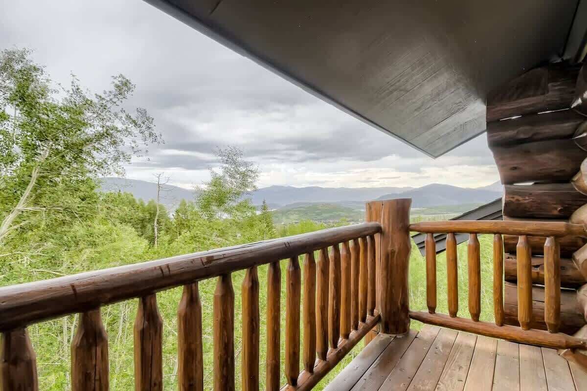 Een houten terras met een hekwerk, uitkijkend op een bergachtig landschap.