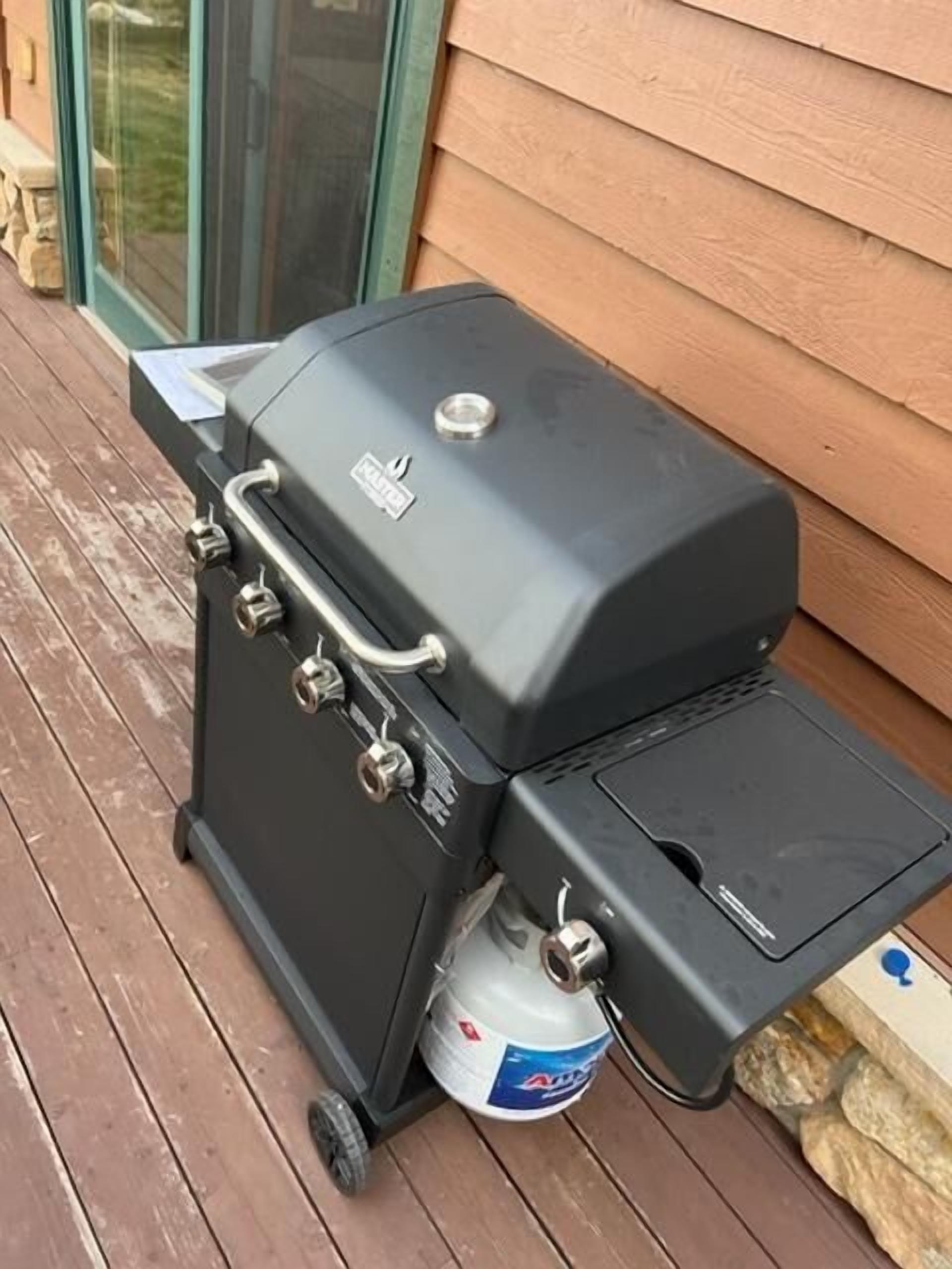 Una parrilla portátil con tanque de gas, ubicada sobre una terraza de madera.