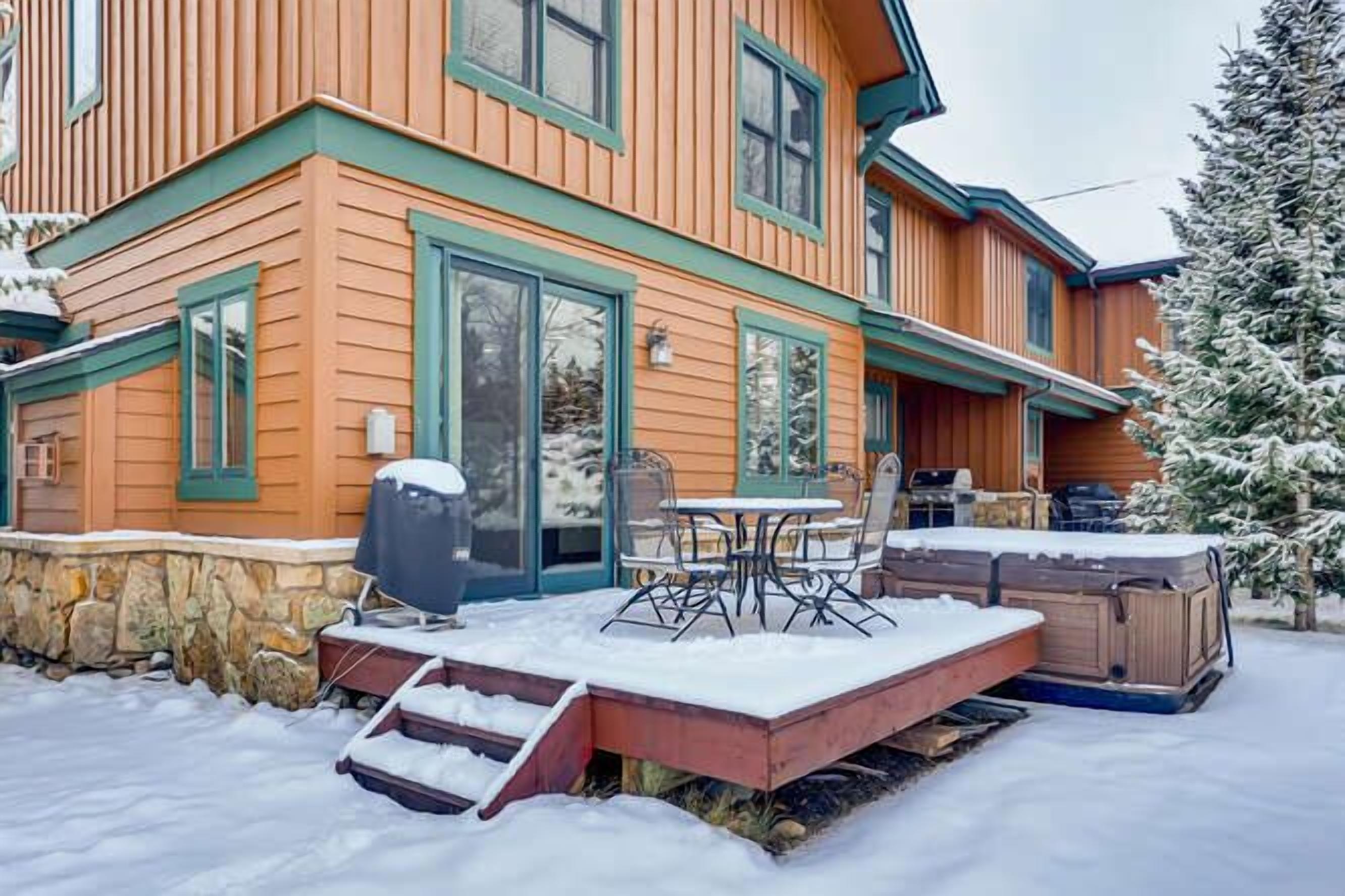 A wooden house with a patio area, outdoor seating, and a hot tub.