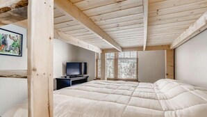 A bedroom with a large bed, wooden ceiling beams, a TV, and a window with blinds. - Family Hot Tub, Mountainscape Chalet! Paradise! (Breckenridge)