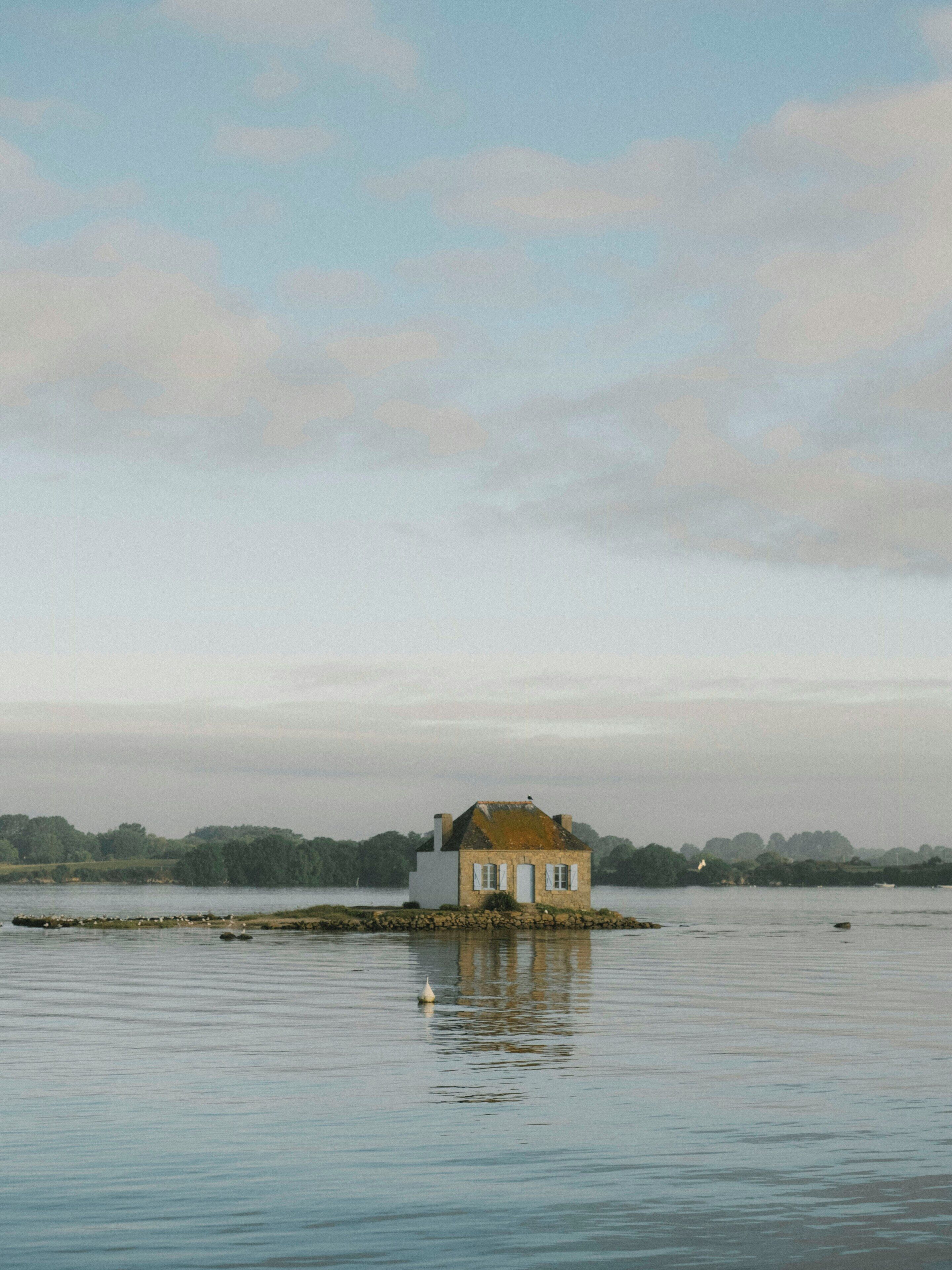 A house on stilts over water with a calm lake and distant trees.