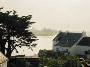 A coastal residential area with houses, a tree, and a view of the sea. - Sea view apartment in Saint Cado Brittany (Belz)