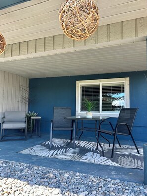Eine Terrasse mit Tisch und Stühlen, einem Blumentopf und einer dekorativen Hängelampe.