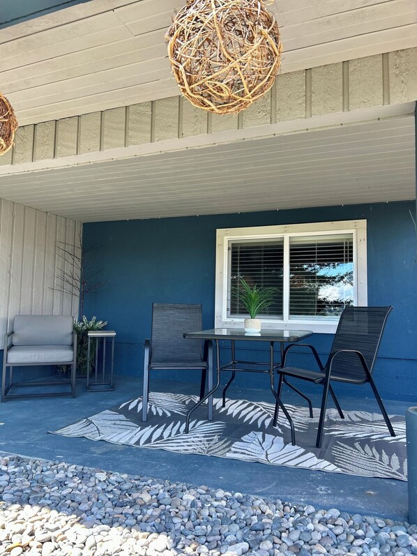 En terrasse med et bord og stole, en potteplante og en dekorativ hængende lampe.
