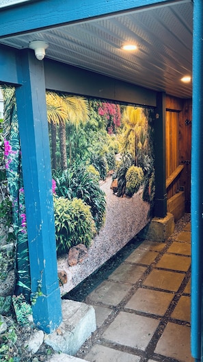 A covered outdoor area with a garden wall, a stone pathway, and a wooden door.