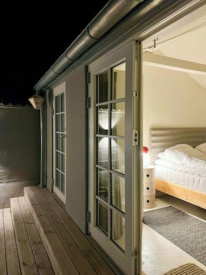A room with a bed, a wooden floor, and a door leading to an outdoor area. - Townhouse from 1862 with sunsets in Thorøhuse (Assens)