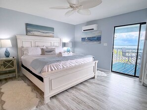 A bedroom with a bed, bedside tables, a ceiling fan, and a view of the outdoors through a glass door. - Bayview 66 Townhome | Orange Beach Condo with Deeded Boat Slip + Boat Launch | Wolf Bay (Orange Beach)
