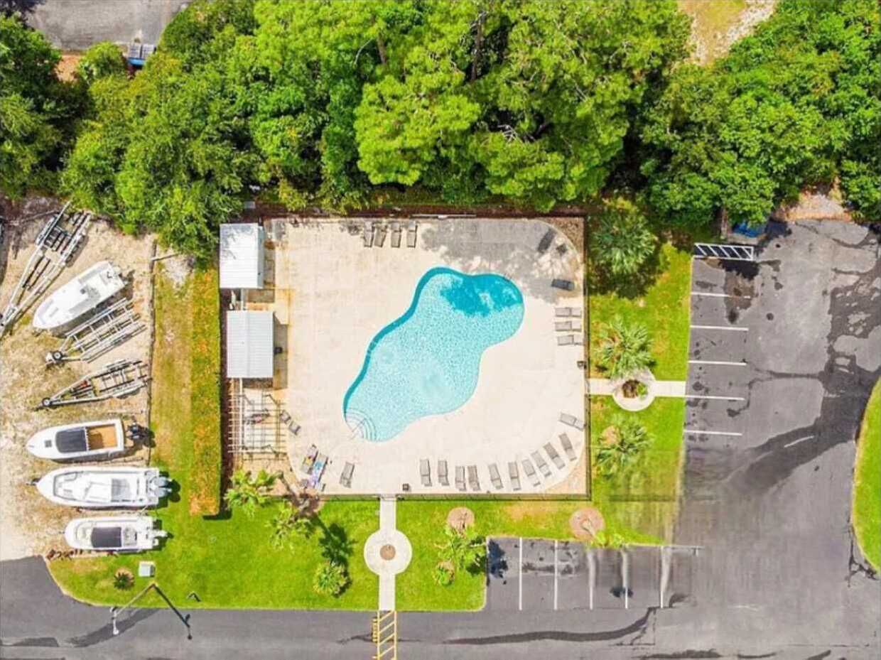 An aerial view of a swimming pool surrounded by a parking area and boats.