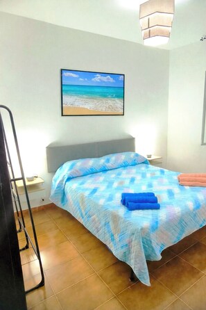 Ein Schlafzimmer mit Bett, Wandfernseher und Blick auf den Strand.
