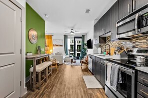 A modern kitchen with dark cabinets, a microwave, and a stove. - 5 mins to Broadway. Downtown. Midtown. Pool. Gym (Nashville)