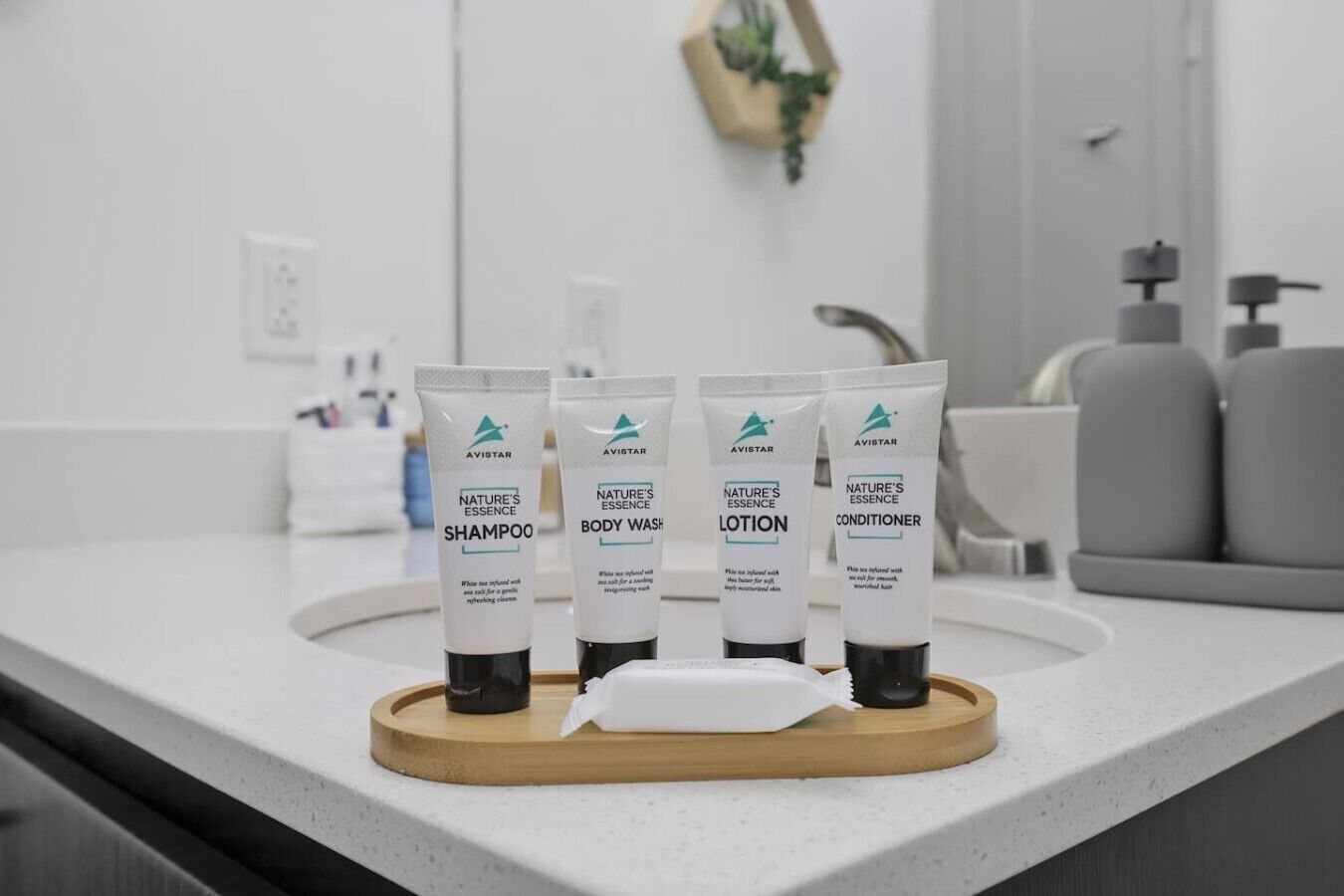 Une salle de bain avec un comptoir sur lequel sont exposées quatre bouteilles de produits de la gamme Avistar Nature's Essence : shampoing, gel douche, lotion et après-shampoing.