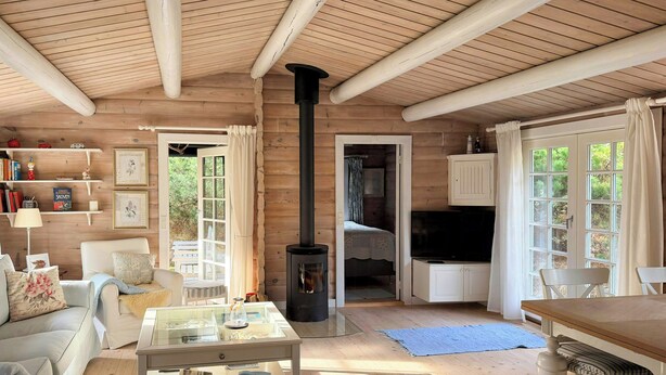 Un acogedor interior de cabaña con techo de madera, chimenea, televisor y comedor.