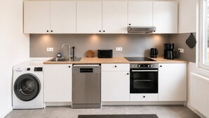 Een kleine keuken met een wasmachine, vaatwasser, oven en koffiezetapparaat.