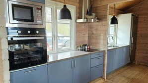 Una cucina con forno a microonde, forno e frigorifero, pareti in legno e una finestra.
