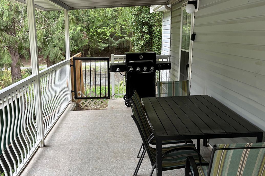 A covered porch with a grill, a table, and chairs.