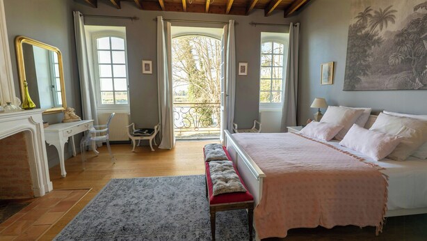 Une chambre à coucher avec un lit, un bureau, une chaise, un banc et une grande fenêtre.