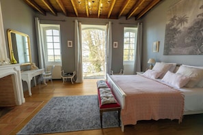Une chambre à coucher avec un lit, un bureau, une chaise, un banc et une grande fenêtre.