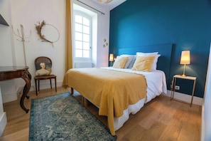 Une chambre à coucher avec un lit, des lampes de chevet, une chaise, un tapis et une fenêtre.