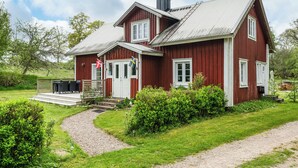 A red wooden house with a porch, a gravel path, and a flag. - Swedish cottage by forest and lake in Småland (Traryd)