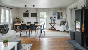 A modern living room with a fireplace, dining area, and a white sofa. - Swedish cottage by forest and lake in Småland (Traryd)