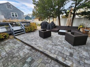Eine Terrasse mit Gartenmöbeln, einem Grill und einer kleinen Holzterrasse.