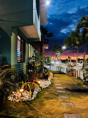 A well-maintained outdoor area with a pathway, potted plants, and a building with a balcony. - Oceanfront Rustic Family Home Fully Equipped for 8 (Camuy)