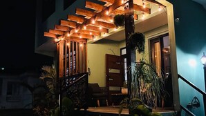 A covered outdoor area with a wooden pergola, steps leading up to a door, and potted plants. - Oceanfront Rustic Family Home Fully Equipped for 8 (Camuy)