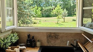 A kitchen with a large window, a sink, and a view of a green garden.