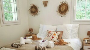 A bedroom with a large bed, two bedside tables, and two windows.