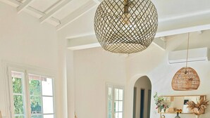 A bright living room with a sofa, chairs, a coffee table, and a hanging light fixture.