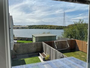 A view of a backyard with a wooden fence, a small shed, and a grassy area. - Lakeland Lettings in the heart of Barrow with view of the Reservoir (Barrow-in-Furness)
