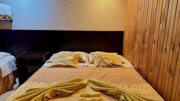 A single bed with a wooden headboard, a bedside table, and two wall-mounted lights.