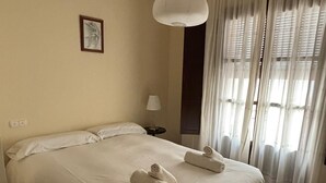 A hotel room with a large bed, a bedside lamp, a ceiling light, and a window with curtains. - Paquita's House (Priego de Córdoba)