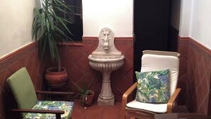 A small, enclosed patio area with two chairs, a table, a potted plant, and a decorative urn. - Paquita's House (Priego de Córdoba)