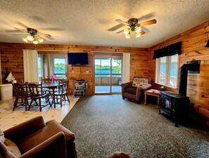 A log cabin interior with a dining area, a sofa, a fireplace, and a television.