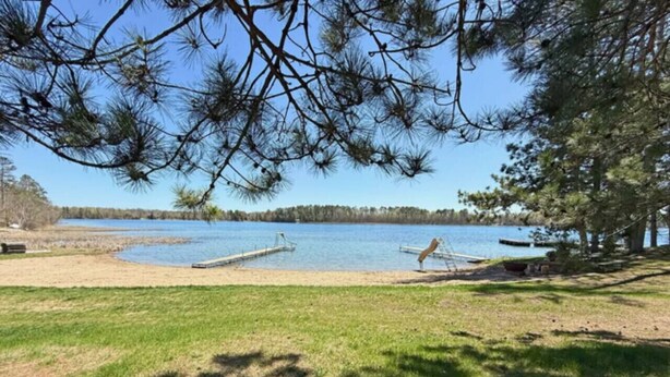 Näkymä järvelle, jossa on laituri, nurmialue ja puita.