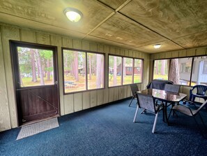 A room with a large window, a door, and a table with chairs.