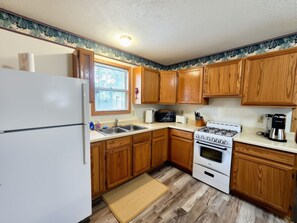 A kitchen with wooden cabinets, a white refrigerator, a stove, and a sink.