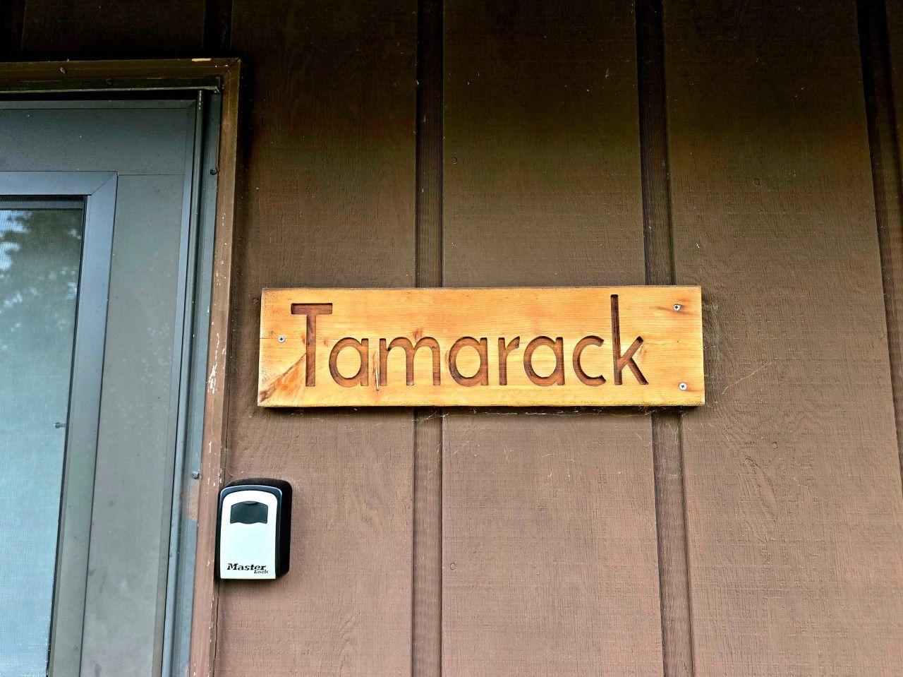 Une plaque en bois portant l’inscription « Tamarack » est fixée à un mur.
