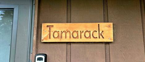 Une plaque en bois portant l’inscription « Tamarack » est fixée à un mur.