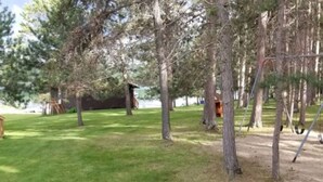 Un espace boisé avec une balançoire et une petite structure en bois.